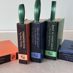 May include: Miniature book replicas of classic novels, including "Frankenstein," "Around the World in Eighty Days," and "Anne of Green Gables." Each book has a green ribbon bookmark and is in a decorative box.