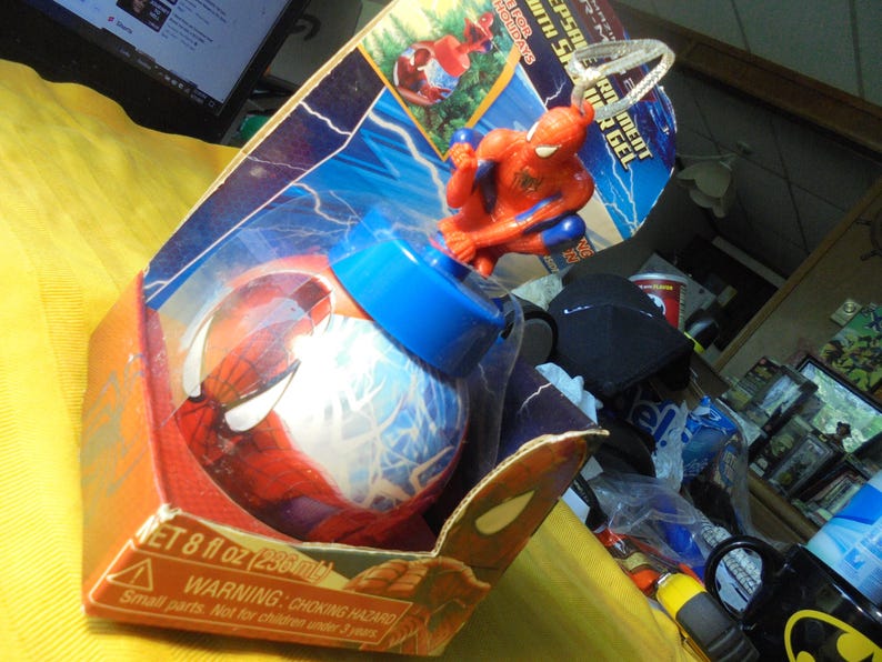 May include: A Spider-Man themed bath gel container in a red and blue spherical bottle with a molded Spider-Man figure on top. The product is housed in a cardboard display box featuring lightning graphics and the text NET 8 fl oz (236 ml).