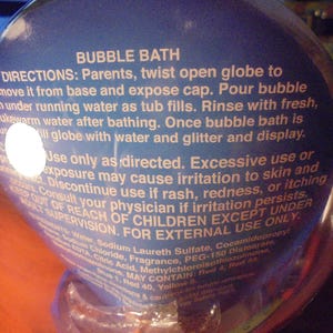 May include: A clear, spherical bubble bath container with blue label text. The label provides directions for use, including warnings about skin irritation and the need for adult supervision. The product is for external use only.
