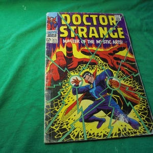May include: Vintage Doctor Strange comic book cover. The cover features Doctor Strange in a blue and purple costume, with red and yellow energy effects. The title "Doctor Strange" is in large yellow letters.