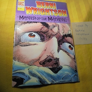 May include: A comic book titled "Berni Wrightson Master of the Macabre" with a close-up illustration of a face with wide eyes. The comic is signed by Bernie Wrightson, dated 1/11/92.