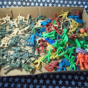 May include: A large collection of assorted plastic toy figures in a cardboard box. The set includes various soldiers, cowboys, and fantasy characters in colors such as green, yellow, red, blue, and orange, all arranged in a jumbled pile.