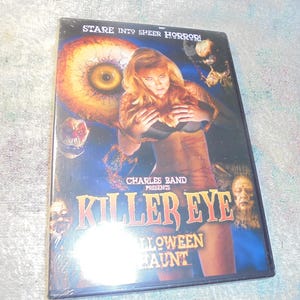 May include: DVD case for the horror film "Killer Eye: Halloween Haunt." The cover features a woman with blonde hair, a large eye, and the film's title in orange and gold lettering. The tagline "Stare into sheer horror!" is at the top.