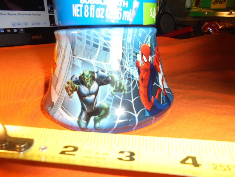 May include: A blue bubble bath bottle featuring Spider-Man and the Green Goblin. The bottle has a cityscape background with a spider web design. The bottle contains 8 fl oz of bubble bath.