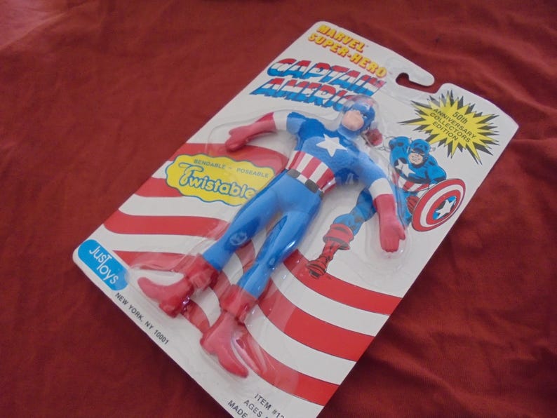 May include: A Captain America action figure in its original packaging. The figure is blue, red, and white, with the words "Captain America" and "Twistable" on the packaging. The packaging also includes the text "50th Anniversary Collectors Edition."