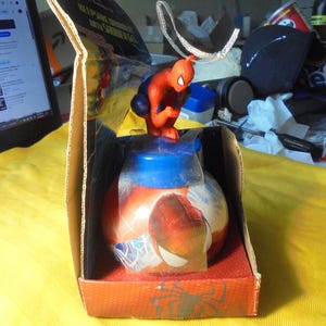 May include: A Spider-Man themed bath product container featuring a red and blue spherical bottle with a character topper. The item is housed in an open cardboard display box with red and black graphics, including a silver hanging loop on top.