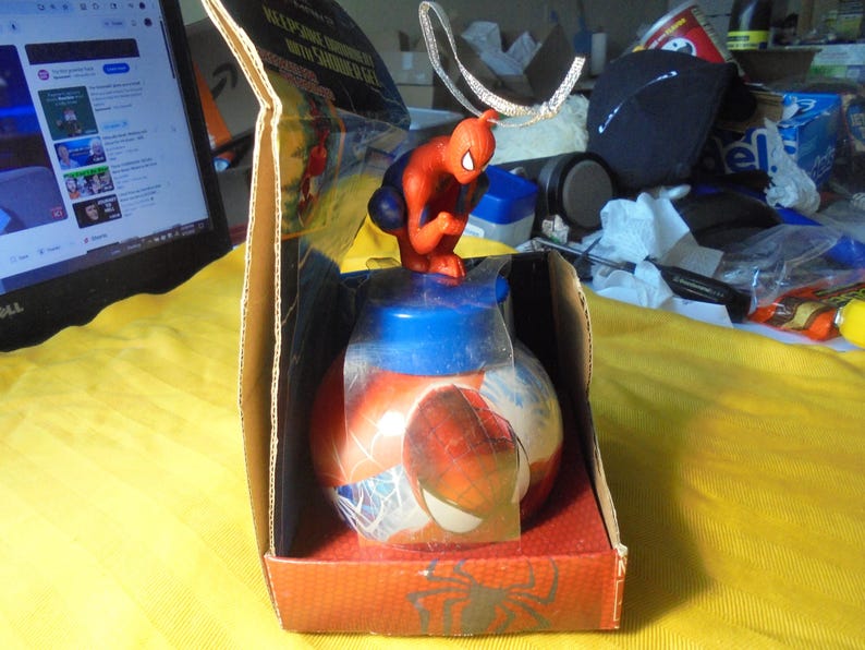 May include: A Spider-Man themed bath product container featuring a red and blue spherical bottle with a character topper. The item is housed in an open cardboard display box with red and black graphics, including a silver hanging loop on top.