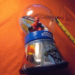 May include: A Spider-Man bubble gum container with a clear plastic globe top. The base is blue and features comic book art of Spider-Man and the Hulk. The container is approximately 6 inches tall and holds 8 fl oz of bubble gum.