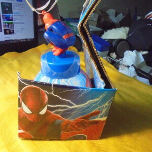 May include: A Spider-Man themed plastic water bottle housed in a cardboard display box. The bottle features a blue cap topped with a small red and blue Spider-Man figurine. The box displays a graphic of Spider-Man with white lightning bolts.