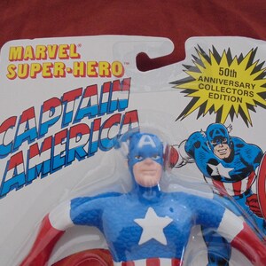 May include: Captain America action figure in packaging. The figure is blue, red, and white, with a star on the chest. The packaging reads "Marvel Super-Hero Captain America" and "50th Anniversary Collectors Edition."
