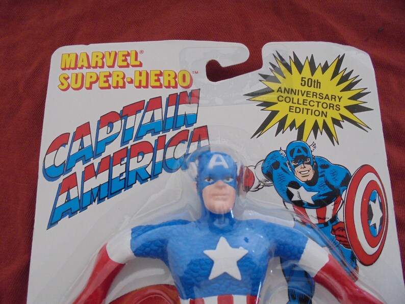 May include: Captain America action figure in packaging. The figure is blue, red, and white, with a star on the chest. The packaging reads "Marvel Super-Hero Captain America" and "50th Anniversary Collectors Edition."