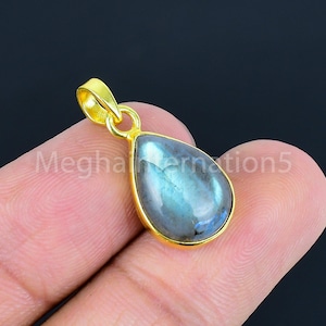 May include: A teardrop-shaped pendant with a gold-colored setting. The pendant features a blue and gray iridescent stone. The text "Meghanation5" is visible on the image.