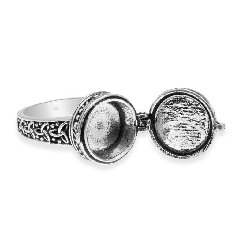 Peut inclure: Bague locket argent&eacute;e avec un compartiment rond ouvert. La bague pr&eacute;sente un motif de n&oelig;ud celtique sur le corps et autour du locket. Le locket est articul&eacute; et s'ouvre pour r&eacute;v&eacute;ler un petit espace vide. La bague est pos&eacute;e sur un fond blanc.