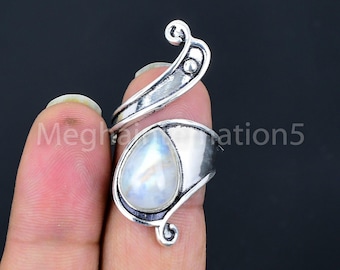 May include: A silver ring with a white moonstone teardrop shaped gemstone. The ring is designed with a curved band and a decorative swirl on the top.