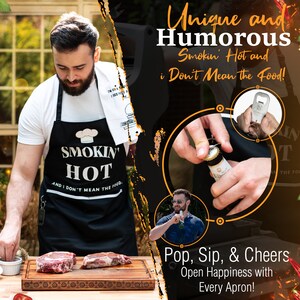 Puede incluir: Un delantal negro con el texto "Smokin' Hot and I Don't Mean the Food!" impreso en &eacute;l. El delantal tiene un abridor de botellas incorporado. El delantal lo lleva una persona que est&aacute; abriendo una botella de cerveza. La imagen tambi&eacute;n muestra a una persona sosteniendo una botella de cerveza y dos filetes en una tabla de cortar de madera.