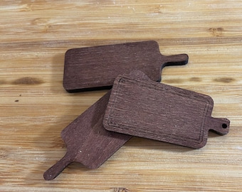May include: Three wooden cutting boards with handles. The boards are brown and have a natural wood grain. One board has a decorative border.