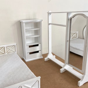Peut inclure: Ensemble de meubles de chambre &agrave; coucher en bois blanc comprenant un cadre de lit, une commode avec des &eacute;tag&egrave;res et des tiroirs et un miroir sur pied avec un porte-v&ecirc;tements.
