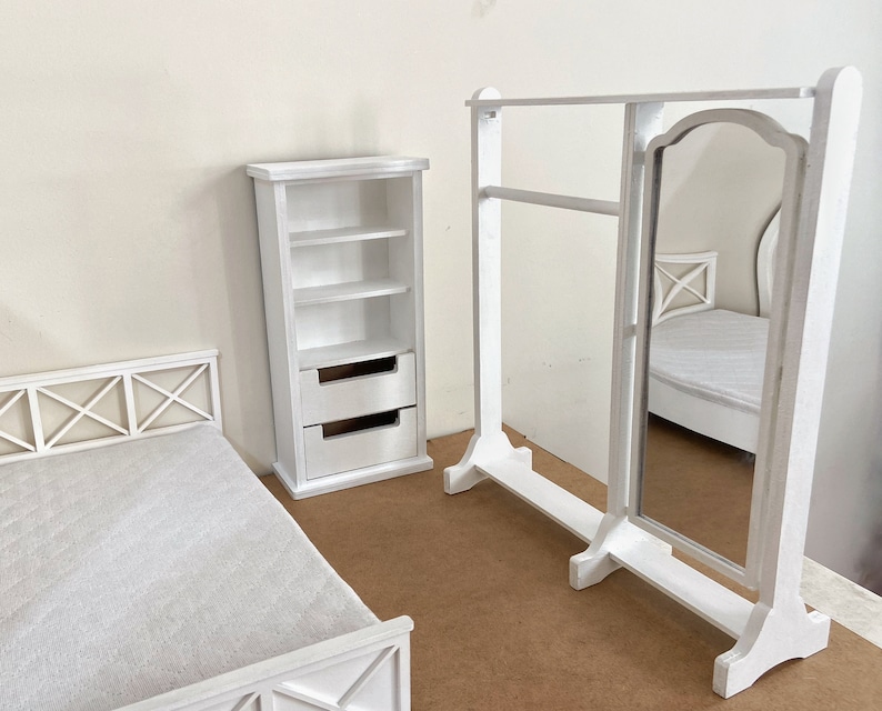 Peut inclure: Ensemble de meubles de chambre &agrave; coucher en bois blanc comprenant un cadre de lit, une commode avec des &eacute;tag&egrave;res et des tiroirs et un miroir sur pied avec un porte-v&ecirc;tements.