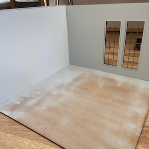 May include: A white room with two windows, each with a grid pattern. The room is empty except for a brown floor.