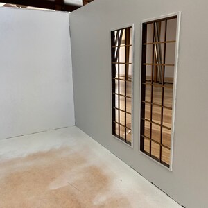 May include: A white room with two windows with brown wooden frames and a white trim. The windows are on a white wall and the floor is a light brown color.