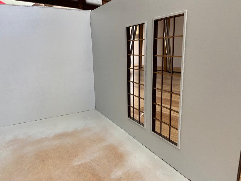 May include: A white room with two windows with brown wooden frames and a white trim. The windows are on a white wall and the floor is a light brown color.