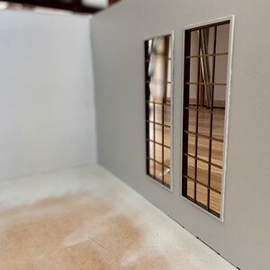 May include: A white room with two windows. The windows have a grid pattern and are framed in white. The floor is a light brown color.