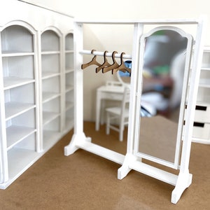 Peut inclure: Ensemble de meubles de maison de poup&eacute;e en bois blanc avec un miroir, des &eacute;tag&egrave;res et un portant &agrave; v&ecirc;tements avec des cintres. L'ensemble est en bois peint en blanc et a un style rustique et champ&ecirc;tre.