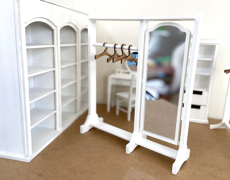 Peut inclure: Ensemble de meubles de maison de poup&eacute;e en bois blanc avec un miroir, des &eacute;tag&egrave;res et un portant &agrave; v&ecirc;tements avec des cintres. L'ensemble est en bois peint en blanc et a un style rustique et champ&ecirc;tre.