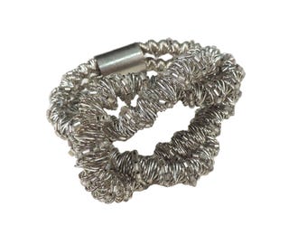 May include: A silver ring made of twisted wire with a magnetic clasp.
