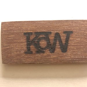 May include: A wooden sign with the letters "KQW" burned into the surface.