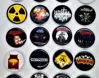 Op de afbeelding: Een verzameling van 16 ronde metalen pinback-knoppen met verschillende heavy metal bandlogo's. De logo's omvatten bands zoals Anthrax, Slayer, Testament en Whiplash. De knoppen zijn zwart, wit en geel met verschillende grafische ontwerpen.