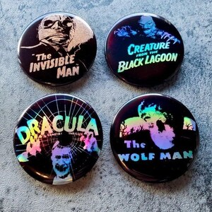 Puede incluir: Cuatro botones negros e iridiscentes con personajes clásicos de películas de terror. Los botones muestran imágenes de Drácula, el hombre invisible, la criatura de la laguna negra y el hombre lobo.