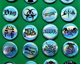 May include: A collection of 16 iridescent metal pinback buttons featuring logos of various heavy metal bands, including Iron Maiden, Dio, Testament, Slayer, Anthrax, Megadeth, and Motorhead.