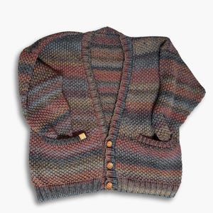May include: A striped cardigan with a V-neck and button closure. The cardigan is made of a soft, textured yarn in shades of gray, brown, and pink.