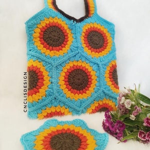 Peut inclure: Un sac fourre-tout en crochet avec un motif de tournesol dans les tons bleu, orange, jaune et marron. Le sac a une seule anse et un petit tournesol en crochet assorti.