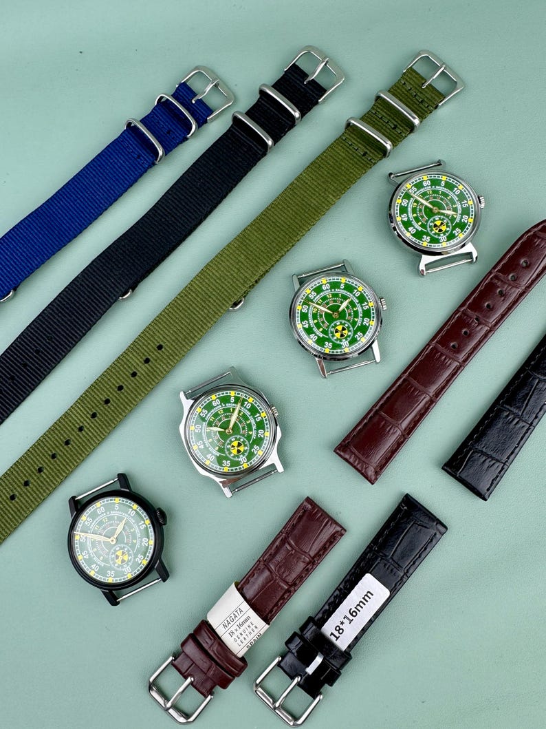 Puede incluir: Un surtido de correas de reloj y relojes. Las correas son de nailon azul, negro y verde oliva, y de cuero marr&oacute;n y negro. Los relojes tienen esferas verdes y blancas con cajas plateadas. Una correa est&aacute; etiquetada "18*16mm".