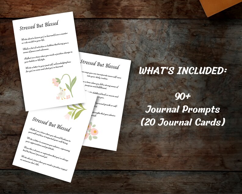 May include: Three printable journal cards with floral illustrations and the text "Stressed But Blessed". Each card features a different journal prompt. The text "WHAT'S INCLUDED: 90+ Journal Prompts (20 Journal Cards)" is displayed at the top of the image.