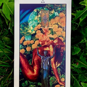 May include: A tarot card with a white border featuring the "Six of Wands." The card depicts a figure with arms raised, a statue, and a background of flowers and a door. The card is set against a backdrop of green foliage.