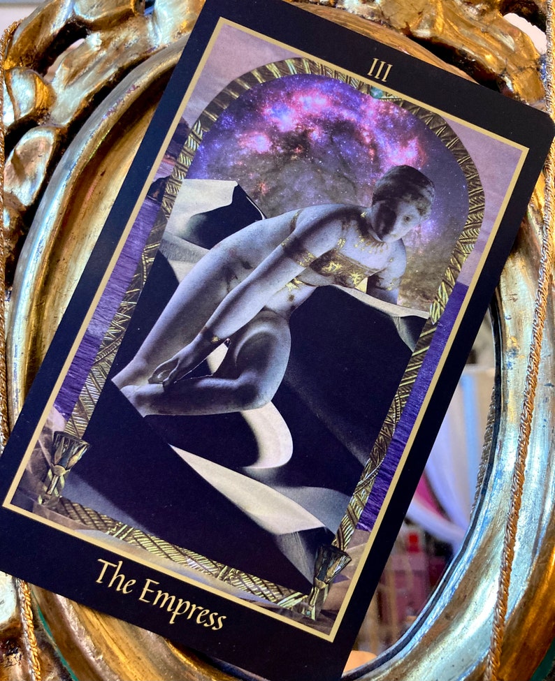 Pu&ograve; includere: La carta dei tarocchi L'Imperatrice con un bordo viola e dorato. La carta presenta una donna con una corona di stelle, seduta su un trono con una luna crescente dietro di lei. Il numero della carta III &egrave; nell'angolo in alto a destra.