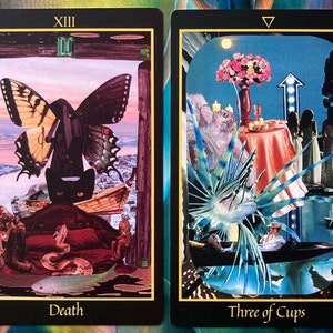 Pu&ograve; includere: Due carte dei tarocchi, Morte e Tre di Coppe. La carta della Morte presenta un gatto nero con una farfalla sopra, una barca e un serpente. La carta del Tre di Coppe presenta tre donne con abiti bianchi, un tavolo con una tovaglia rossa e un pesce con pinne blu e verdi.