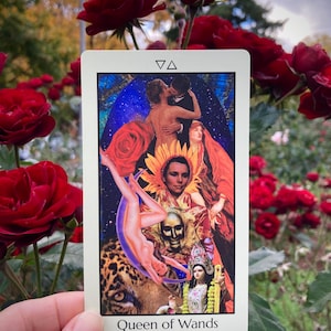 May include: A tarot card titled "Queen of Wands" features a collage of images including a couple kissing, a woman falling, and a deity. The card has a white border and is held in front of a background of red roses.