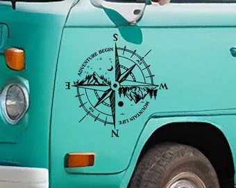 May include: A black and white compass sticker with the text "The Mountain Life" and "Adventure Begin" on a turquoise van.