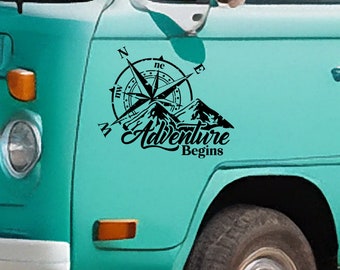 Puede incluir: Calcomanía de vinilo en blanco y negro de una brújula con montañas y el texto "Adventure Begins". La calcomanía se aplica al costado de una camioneta azul turquesa.