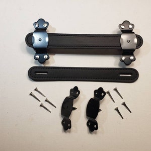 May include: A set of black leather handles with metal hardware and screws. The handles are designed for attaching to a suitcase or bag.