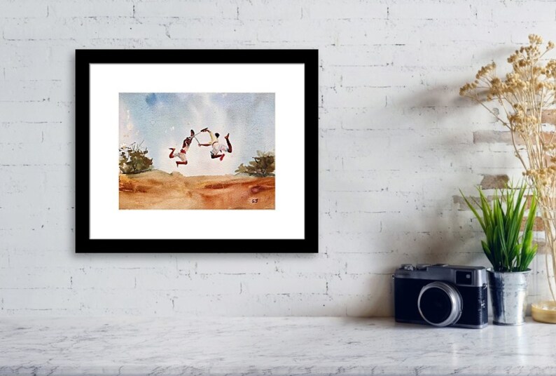 May include: Watercolor painting of two people jumping in the air with their arms outstretched. The painting is set against a blue sky with white clouds. The people are wearing red and white clothing. The painting is framed in black.