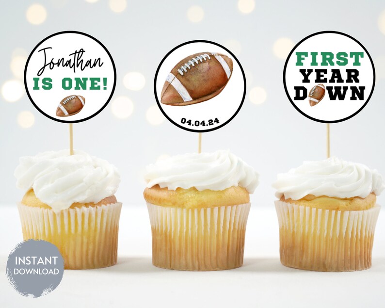 Puede incluir: Tres cupcakes con glaseado blanco cubiertos con toppers redondos de papel para cupcakes con un dise&ntilde;o de f&uacute;tbol. Los toppers tienen el texto "Jonathan is one!"  "First Year Down" y "04.04.24".