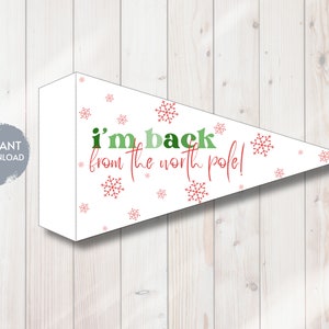 Op de afbeelding: Witte wimpel met de tekst "I'm back from the north pole!" in groen en rood. De vlag is versierd met rode sneeuwvlokken. Een grijze cirkel met de woorden "INSTANT DOWNLOAD" staat links.