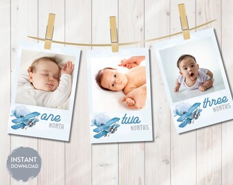 May include: Three blue and white photo cards with a watercolor airplane design. Each card has a different number on it, one, two, and three. The cards are hanging on a string with clothespins.