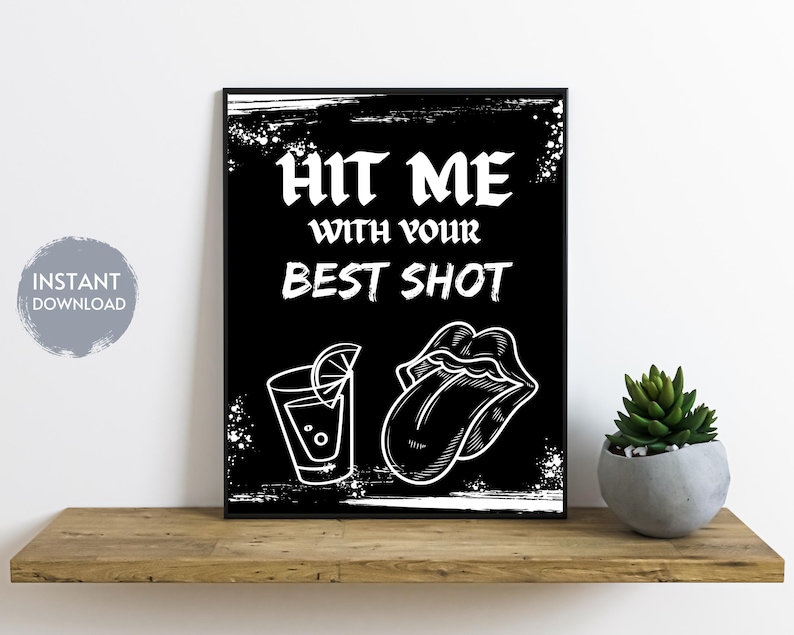 May include: Black and white printable wall art with the text "Hit me with your best shot" and illustrations of a shot glass with a lime wedge and a tongue sticking out.