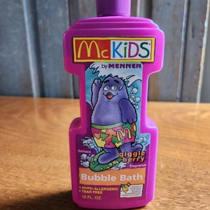 May include: Purple plastic bottle of McKids by Mennen bubble bath with a cartoon character named Grimace on the front. The bottle is labeled "giggle berry fragrance" and "Bubble Bath". It is a hypo-allergenic and tear free formula. The bottle contains 12 fl oz.